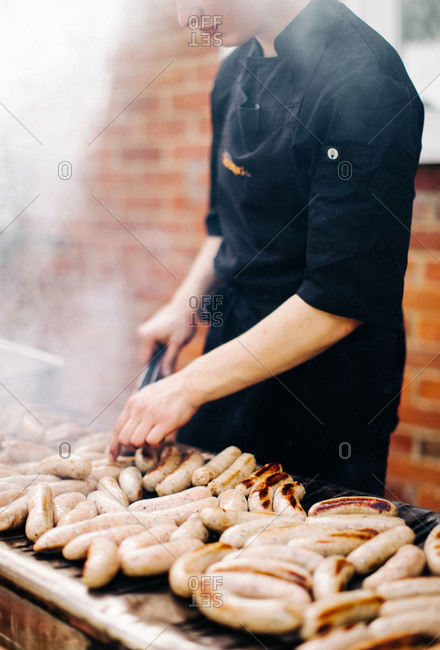 Chef grilling sausages at outdoor grill for banquet
