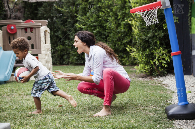 Woman playing basketball with her son in the backyard