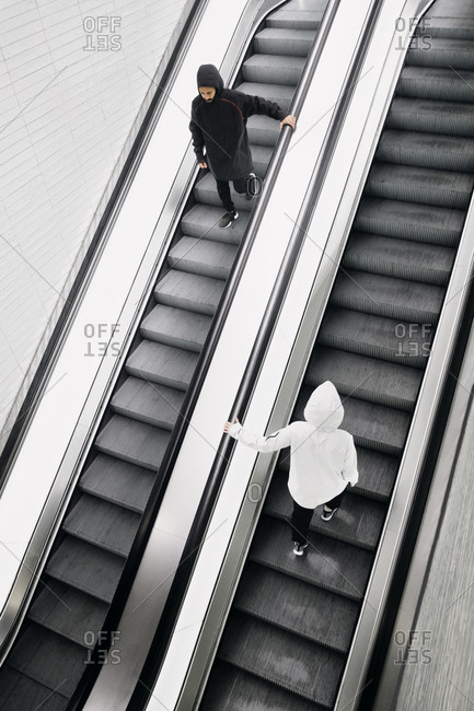 Two people going up and down an escalator