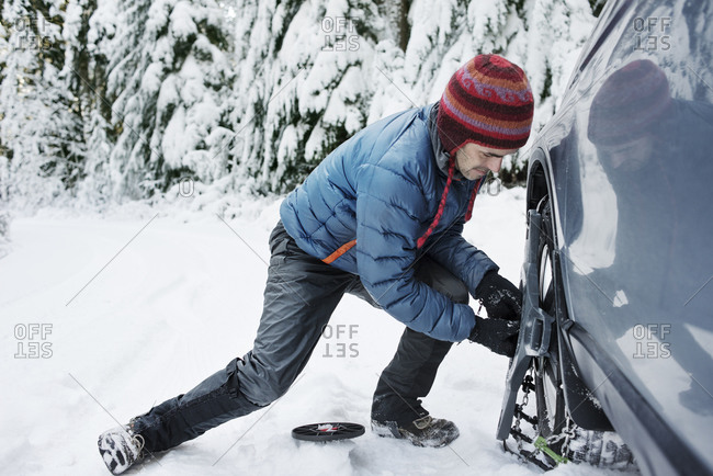 Man putting chains on his car tires
