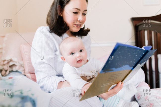 Baby girl in her mother\'s lap as she reads a story
