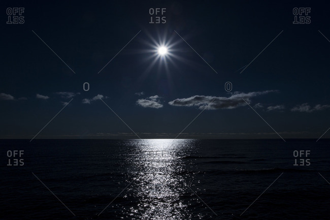 Moon shining over ocean at night