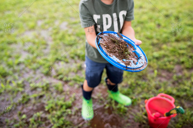 Boy making mud pies after a rain storm