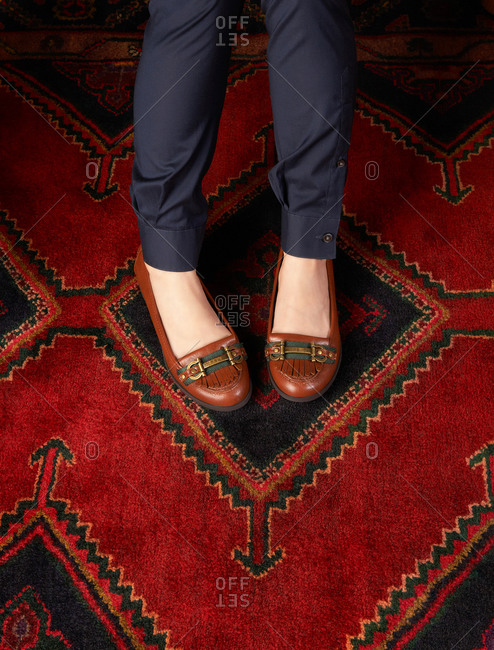 Woman\'s loafers on a deep red carpet