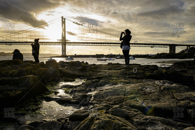 People taking photos of the Golden Gate Bridge at sunset