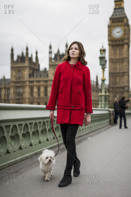 Young woman wearing red jacket walking with her dog
