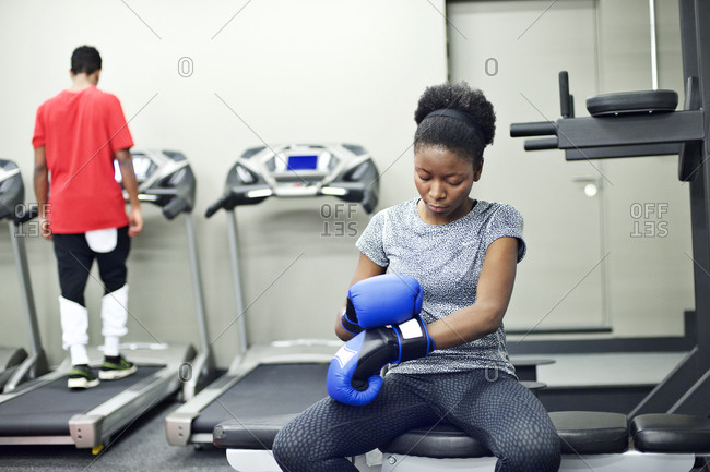 Young woman putting on boxing gloves in her company\'s gym
