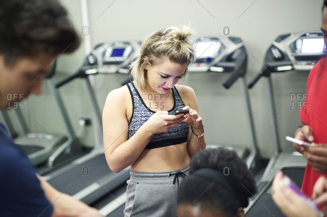Young woman standing in her company gym using her phone
