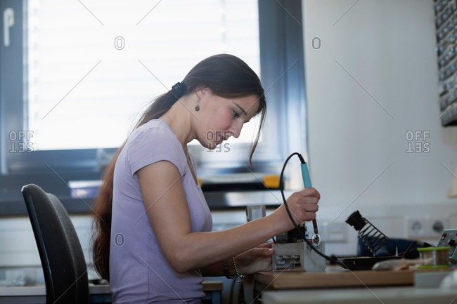 Female technician soldering electronic components in an industrial plant, Freiburg Im Breisgau, Baden-Wurttemberg, Germany