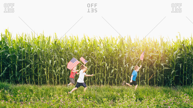 Kids running at a cornfield with American flags