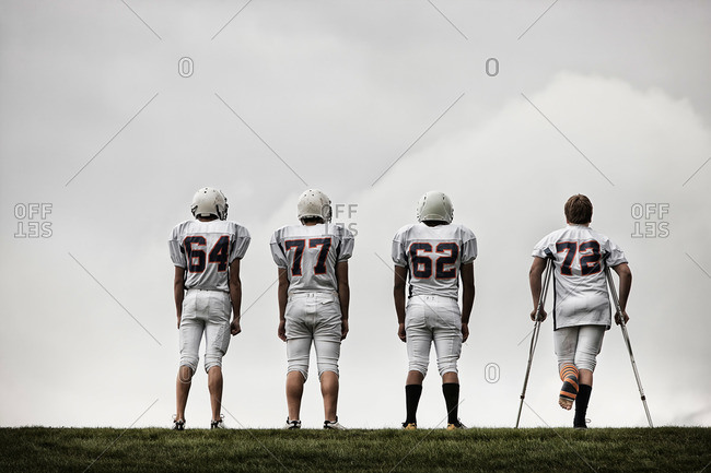 Rear view of a group of four American football players in sports uniform