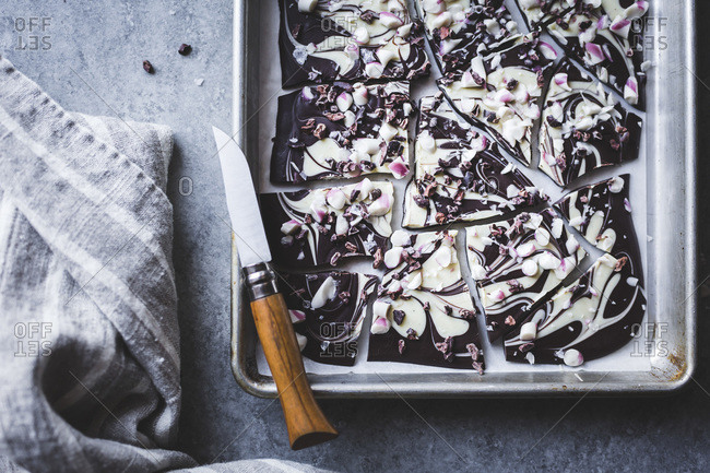 Close up of all-natural dark chocolate peppermint bark with cacao nibs and flaky salt on a baking dish