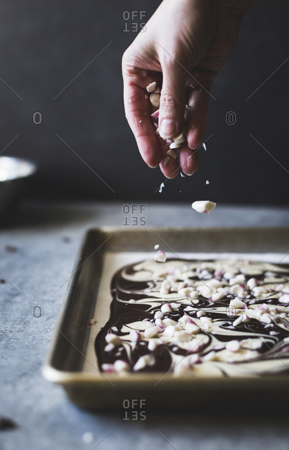 Person sprinkling peppermint onto baking pan with all-natural dark chocolate