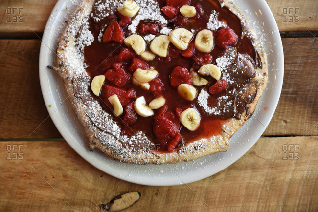 Dessert pizza with chocolate sauce with bananas and strawberries