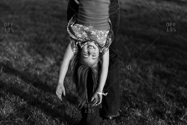 Parent dangling happy daughter upside down