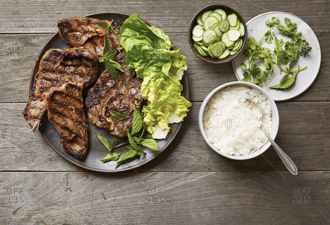 Plate of grilled Sichuan cumin lamb chops with  pickled cucumbers and rice