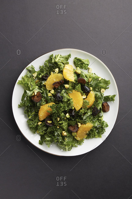 Overhead view of kale salad with mandarin orange sections and figs