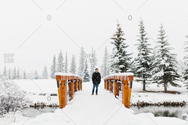 Man standing on a bridge during the snow
