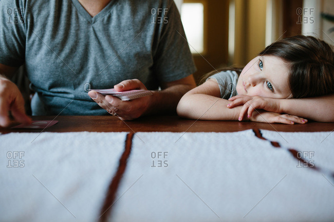 Girl resting while dad deals cards