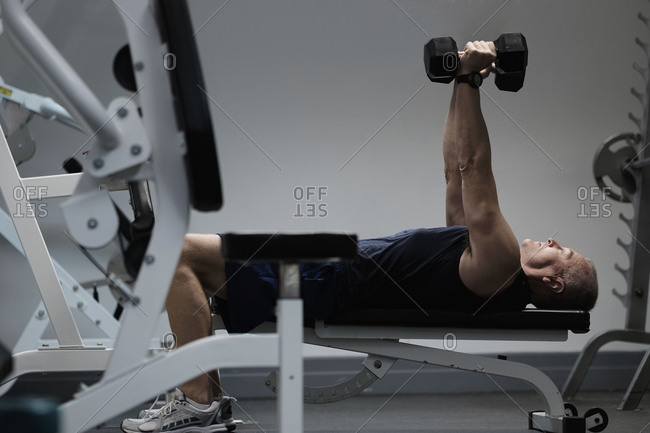 Man exercising with dumbbells on weight bench