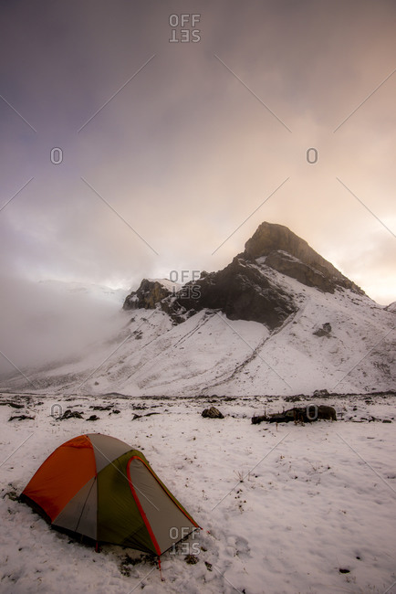 A tent in front of a mountain peak on the snow