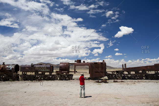 A man takes a photo of a deserted train in the Atacama Desert