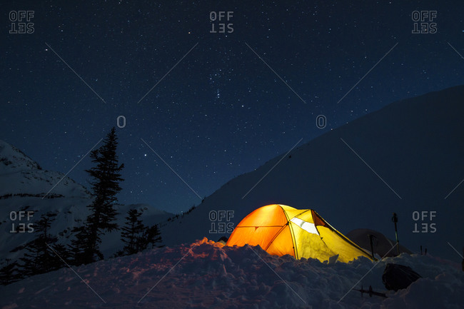 A headlamp is used to light up a tent below a starry night sky in British Columbia, Canada