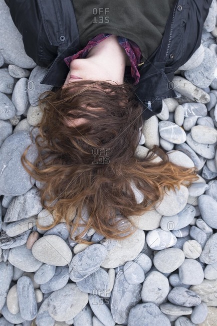 Woman lying on rocks with hair covering her face