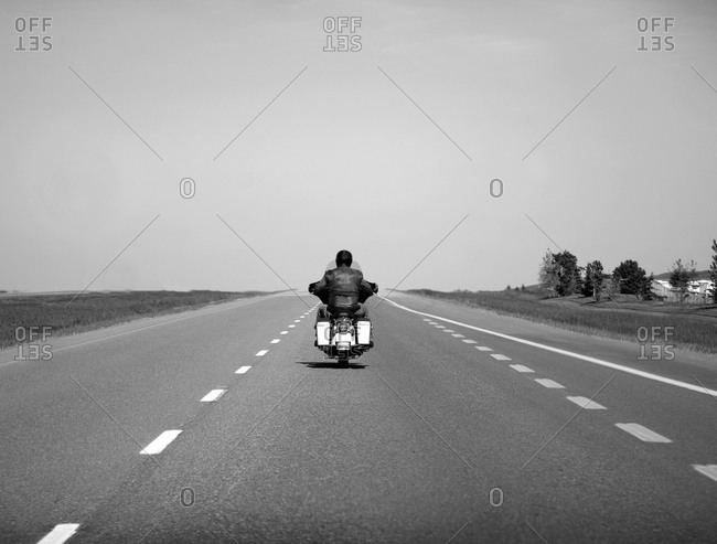 Lone person on motorcycle riding down the open highway in Alberta, Canada