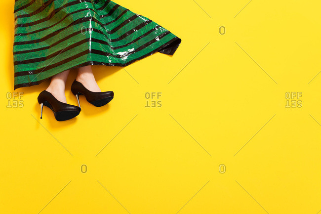 Feet and skirt of woman in dress made of black plastic and green sticky tape