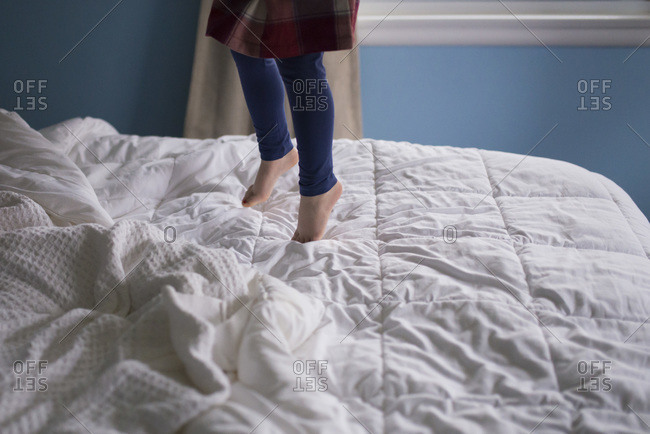 Girls feet jumping on white bedspread