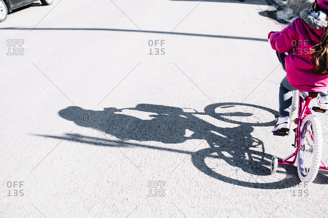 Shadow of young girl riding a bike with training wheels