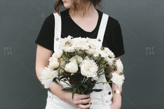 Woman dressed in white and black holding a bouquet of white flowers