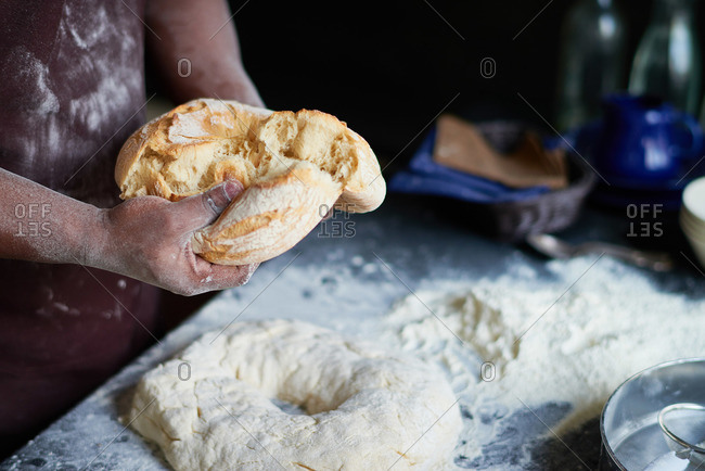 Baker tears apart a freshly baked loaf of bread