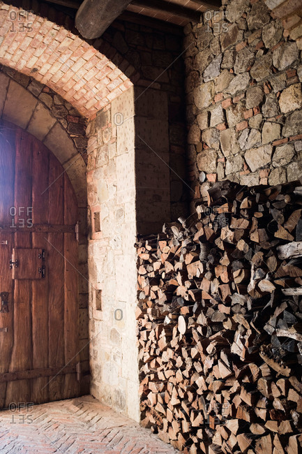 Firewood stacked near an arched doorway in a Tuscan-inspired castle