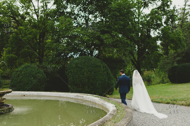 Bride and groom walking by a fountain