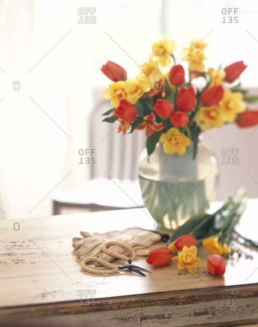 Tulips and daffodils in a vase on a rustic table