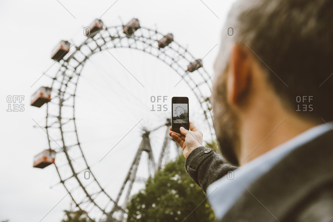 Man taking a picture of big wheel with his smartphone at Prater public park in Vienna