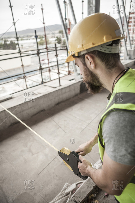 Construction worker using tape measure in construction site