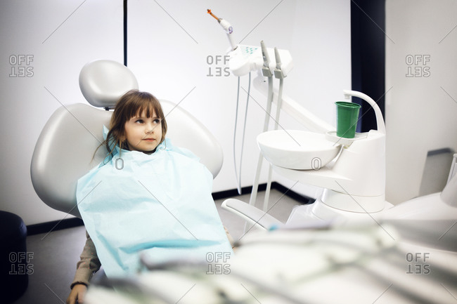 Girl wearing a dental bib sitting in dentist chair
