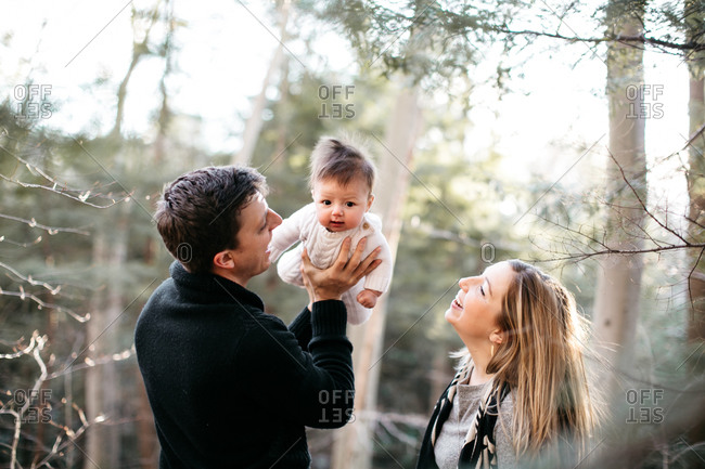 Adoring new parents gaze at their cute baby in the woods