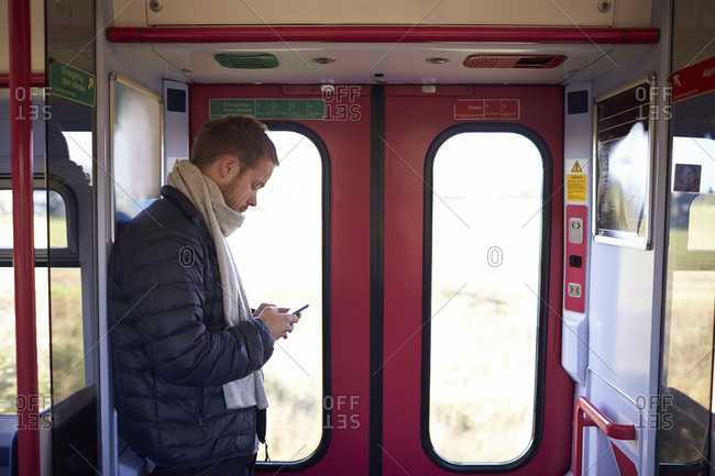 Man Standing In Train Carriage Sending Text Message