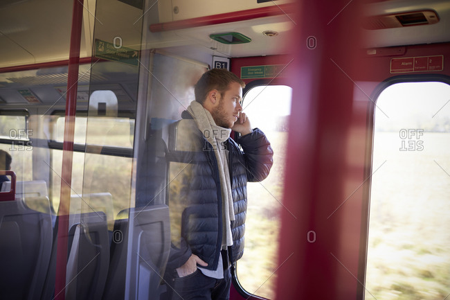 Man Standing In Train Carriage Talking On Mobile Phone