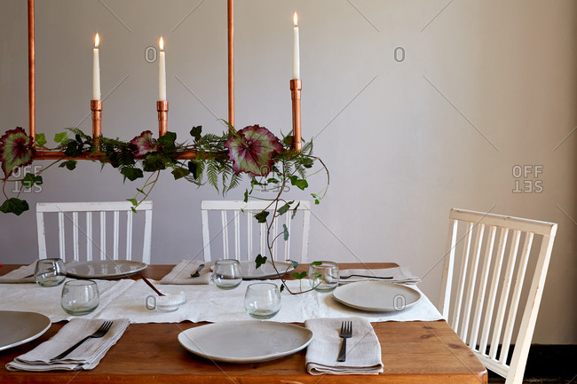 Wood farm table with place settings framed by a copper chandelier