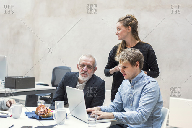 Business people looking at a laptop in a meeting