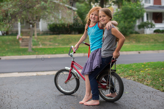 Two girls hugging on a banana seat bicycle