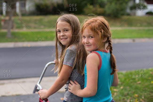 Two girls sitting on a banana seat bicycle