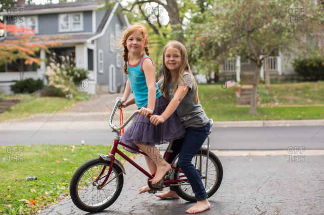 Two girls on a red banana seat bicycle