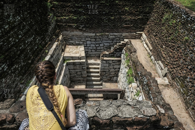 Woman looking down at ruins in Sri Lanka