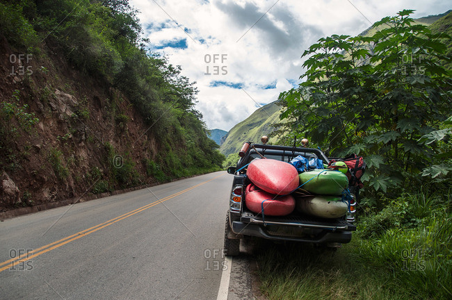 Truck packed with kayaks and river gear parked on road in wilderness